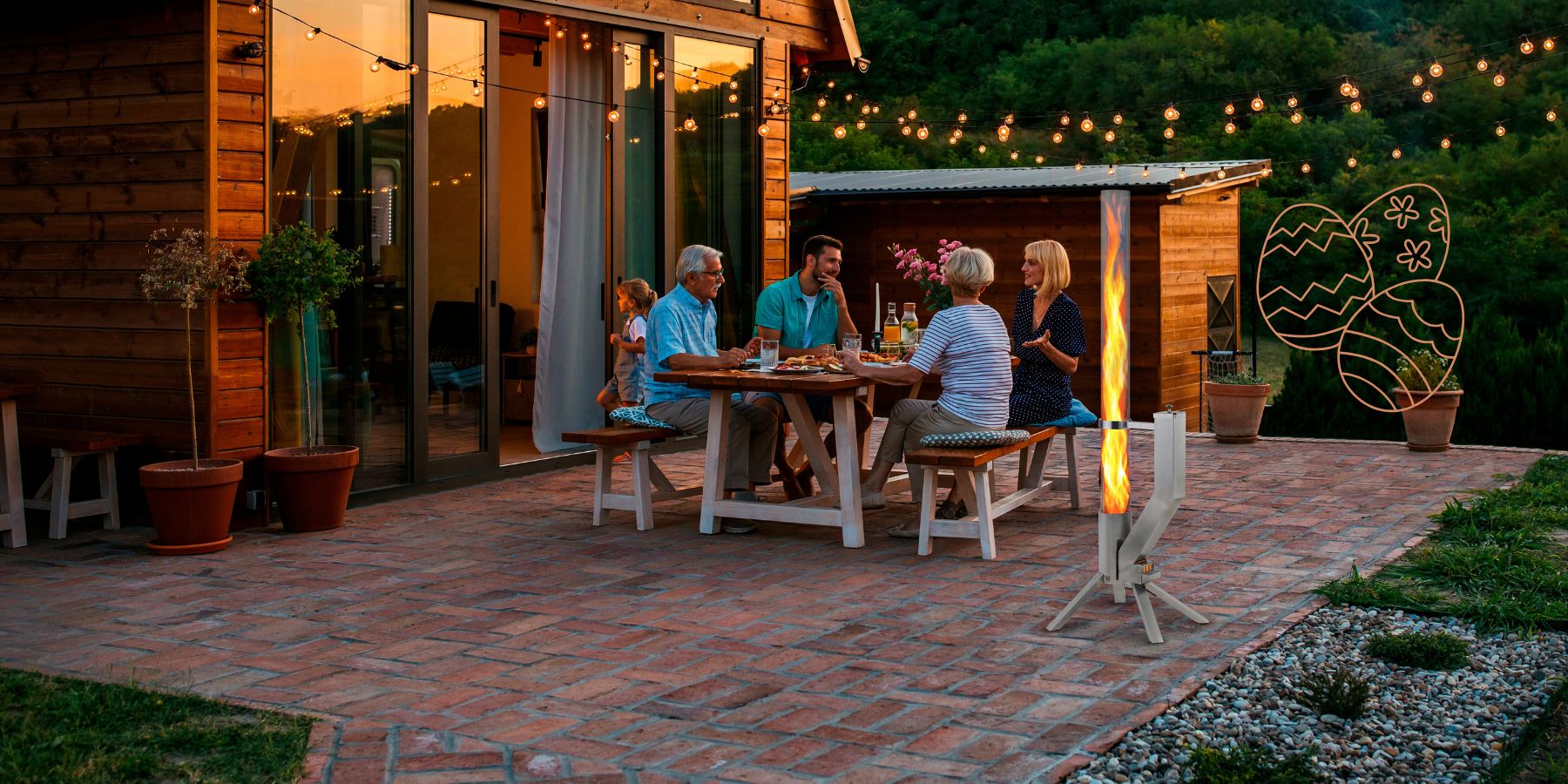 Familie beim Osteressen auf der Terrasse mit dem Gardenflare Feuerrohr als stilvolle Feuerquelle im Vordergrund.