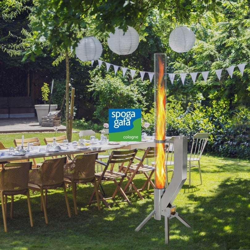 Garten mit festlich gedecktem Tisch, im Vordergrund das Premium Feuerrohr in silber von Gardenflare mit hoher Flamme