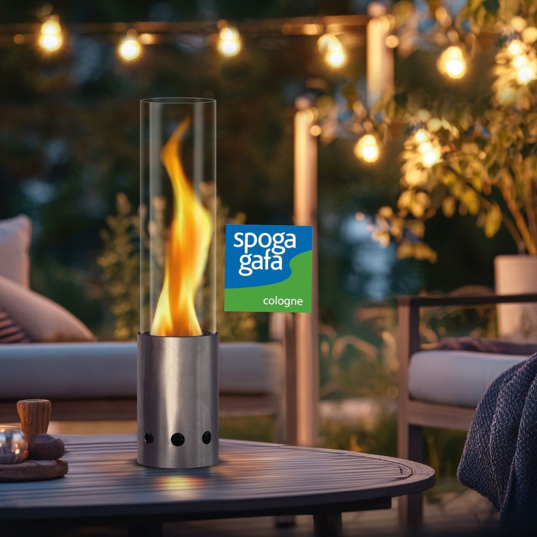 Silbernes Tischfeuer von Gardenflare auf rundem Holztisch bei Abendstimmung und Hinweis auf spoga+gafa-Messe.