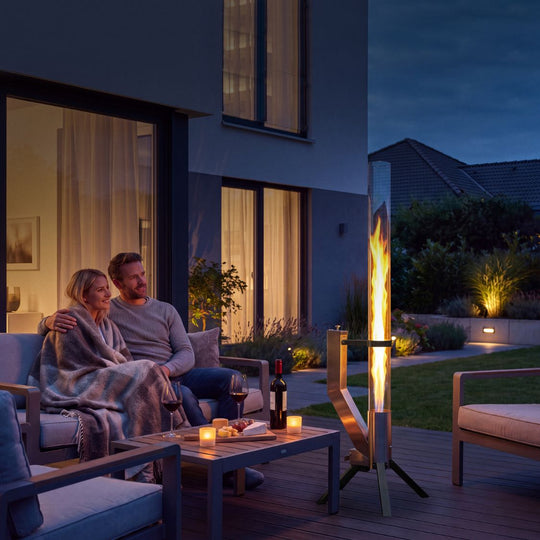 Gardenflare Klassik Multicolor Feuerrohr mit schwarzem Fuß am Abend auf Terrasse
